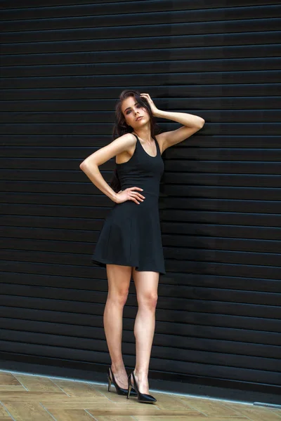 Morena mujer joven en sexy vestido negro, estudio de la pared interior —  Fotos de Stock