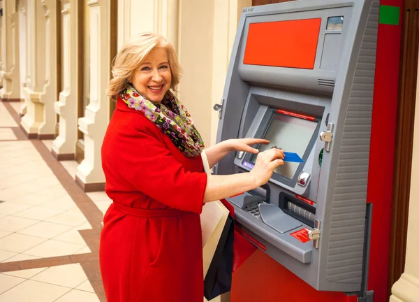 Happy pensioner withdraws cash from an ATM — Stock Photo, Image