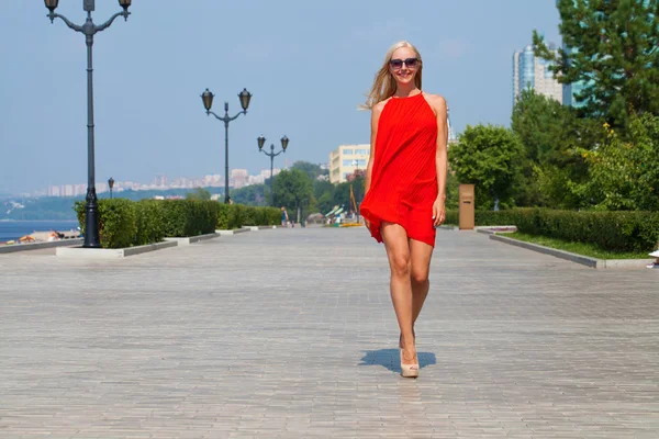 Jeune belle femme en robe rouge marchant dans la rue d'été — Photo