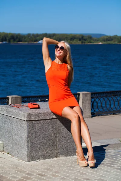 Mladá krásná žena v oranžových šatech na letní ulici — Stock fotografie