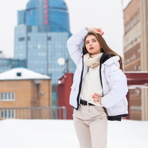 Fshion girl in a white down jacket and beige pants posing outdoo — 스톡 사진