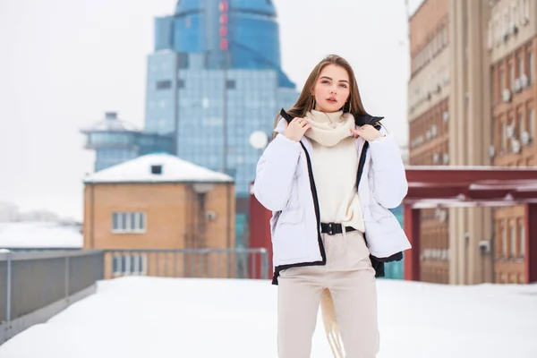 Cojín chica en una chaqueta blanca y pantalones beige posando al aire libre — Foto de Stock