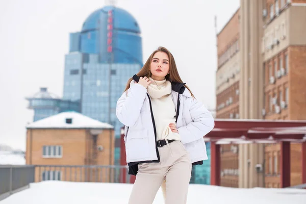 Fshion girl in a white down jacket and beige pants posing outdoo — 스톡 사진