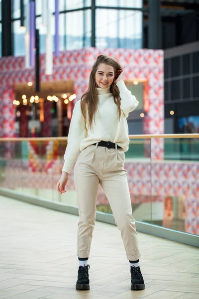 Porträtt av en ung vacker kvinna i beige tröja och byxor p — Stockfoto