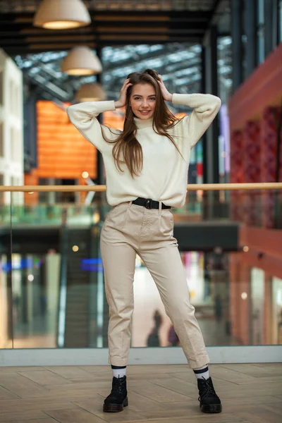 Porträtt av en ung vacker kvinna i beige tröja och byxor p — Stockfoto