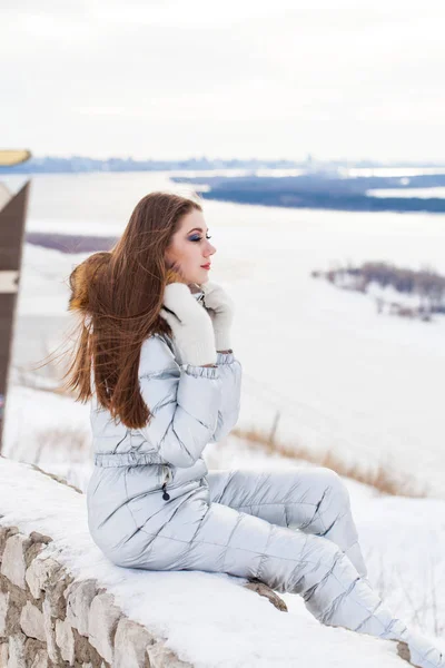 Jeune femme brune en costume de ski argenté posant sur une colline — Photo