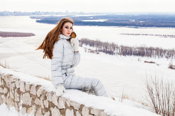 Ung brunett kvinna i en silver skiddräkt poserar på en kulle — Stockfoto