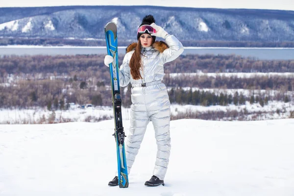 Young brunette woman in a silver ski suit posing on a hilltop — Stock Photo, Image