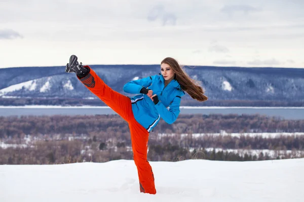 Młoda brunetka w kombinezonie narciarskim pozująca na szczycie wzgórza — Zdjęcie stockowe