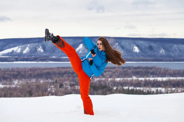 Young brunette woman in a ski suit posing on a hilltop — Stock Photo, Image