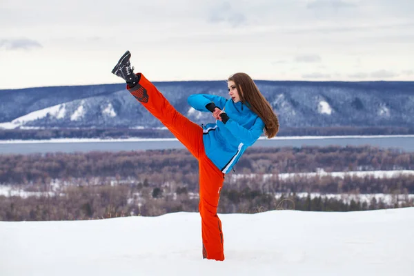 若いですブルネット女性でスキースーツposingオンザ丘の上 — ストック写真