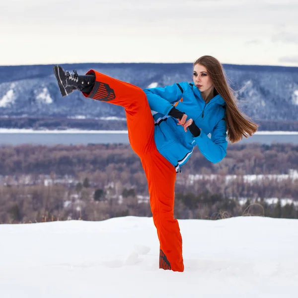 Young brunette woman in a ski suit posing on a hilltop — Stock Photo, Image