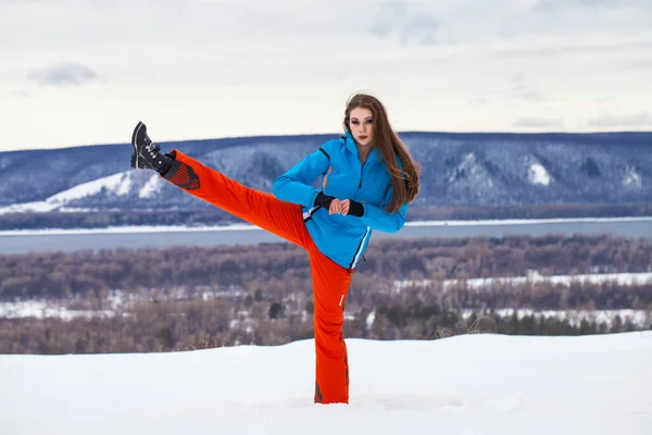 Young brunette woman in a ski suit posing on a hilltop — Stock Photo, Image