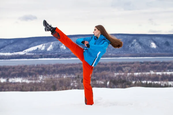 Young brunette woman in a ski suit posing on a hilltop — Stock Photo, Image