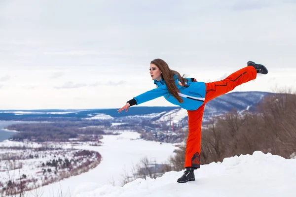 Joven morena en traje de esquí posando en una colina —  Fotos de Stock