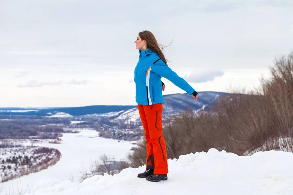 Jong brunette vrouw in een ski pak poseren op een heuveltop — Stockfoto