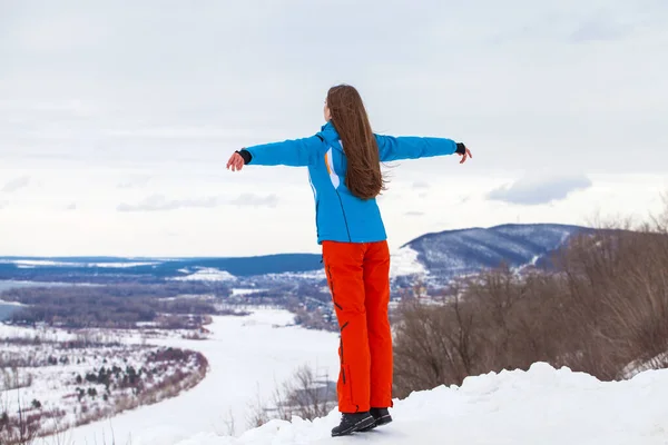 Jong brunette vrouw in een ski pak poseren op een heuveltop — Stockfoto