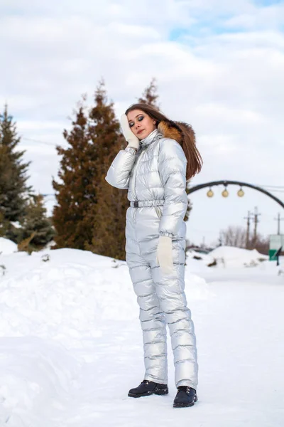 穿着银色滑雪服的年轻黑发女子站在山顶上 — 图库照片