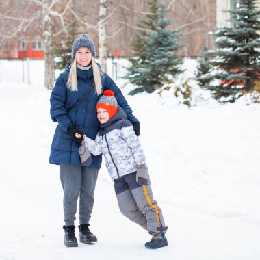 Mavi ceketli mutlu anne ve arka planda bir oğul. 