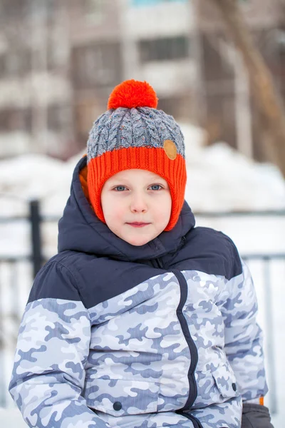 Retrato de un niño pequeño en un sombrero de punto rojo en el parque de invierno — Foto de Stock