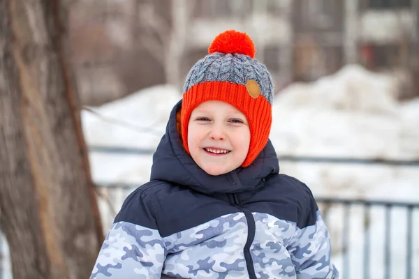 Portret van een jongetje met een rode gebreide muts in het winterpark — Stockfoto