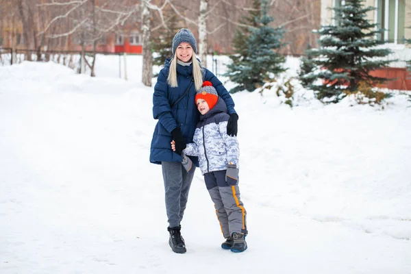 Happy mother in a blue down jacket and a son on a background of — Stock Photo, Image