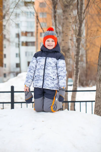 Ritratto di un bambino con un cappello rosso a maglia nel parco invernale — Foto Stock