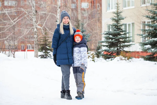 Happy mother in a blue down jacket and a son on a background of — Stock Photo, Image