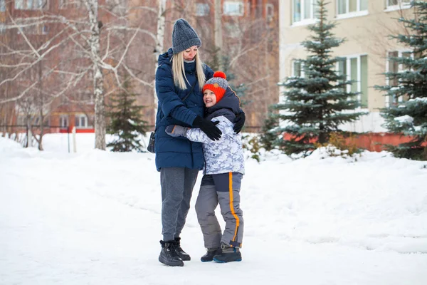 Happy mother in a blue down jacket and a son on a background of — Stock Photo, Image