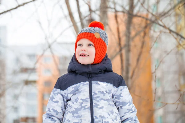 Portrét malého chlapce v červeném pleteném klobouku v zimním parku — Stock fotografie