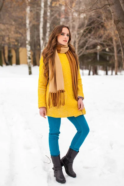 Young beautiful woman in yellow coat walking winter park — 스톡 사진