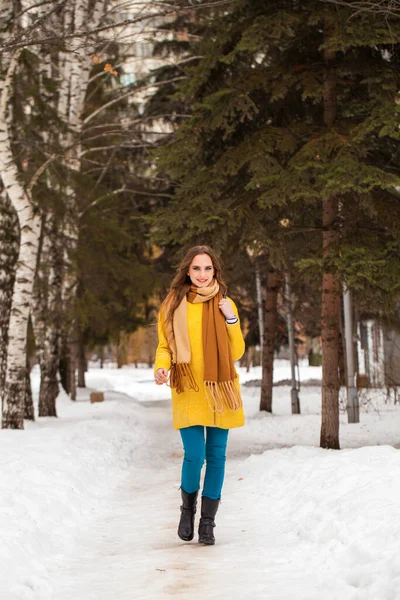 Молодая красивая женщина в желтом пальто ходьба зимний парк — стоковое фото