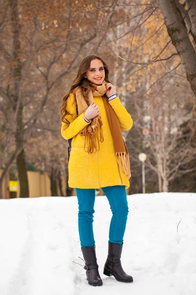 Young beautiful woman in yellow coat walking winter park — 스톡 사진