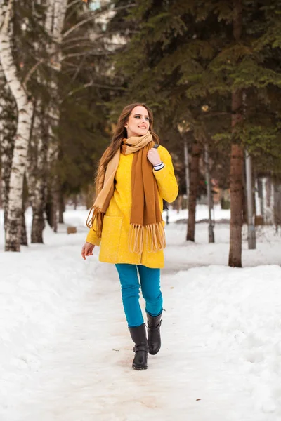 Jonge mooie vrouw in gele jas wandelen winterpark — Stockfoto