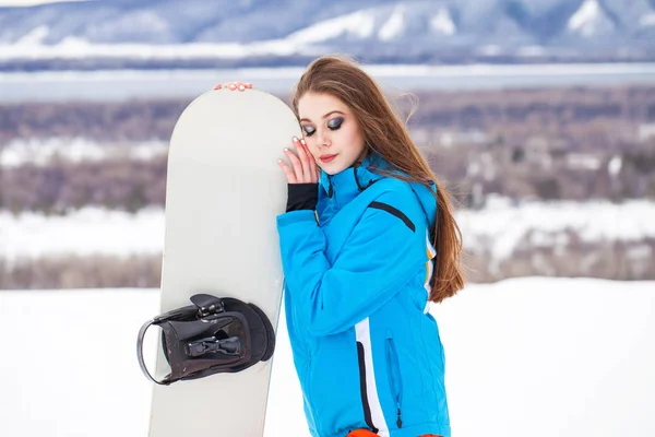 Retrato de una joven hermosa morena con una tabla de snowboard —  Fotos de Stock