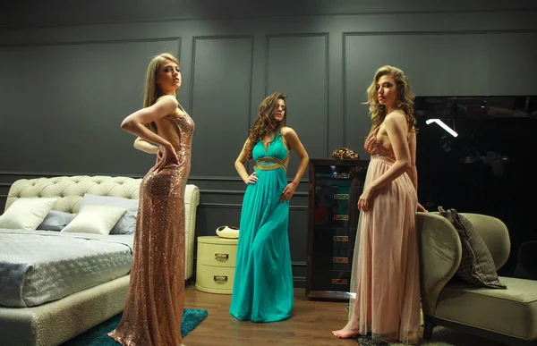 Três mulheres jovens em vestidos de noite posando em interio caro — Fotografia de Stock