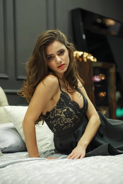 Siyah gece elbisesi giymiş, mobilyada poz veren seksi esmer kadın. — Stok fotoğraf
