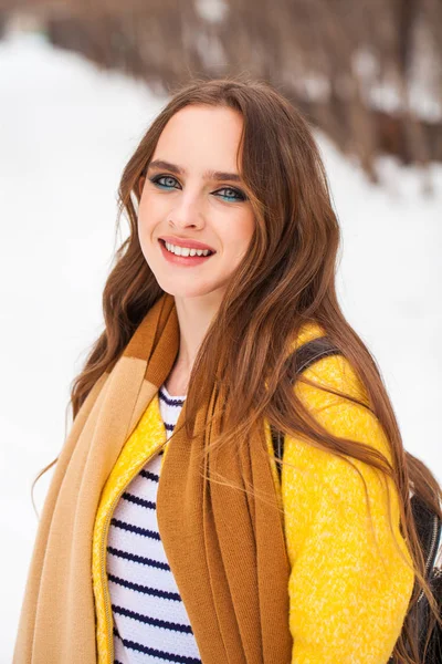Красивая девушка в желтом пальто позирует на фоне зимы — стоковое фото