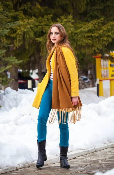 Young beautiful woman in yellow coat walking winter park — Stock Photo, Image