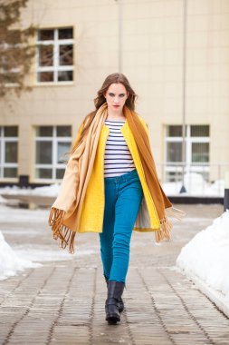 Sarı ceketli güzel bir kadın kış parkında yürüyor.