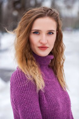 Kış parkında poz veren güzel sarışın bir kadının portresi.