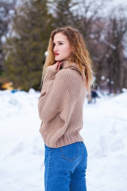 Kışlık parkta bej renkli süveter giyen güzel bir kadının portresi.