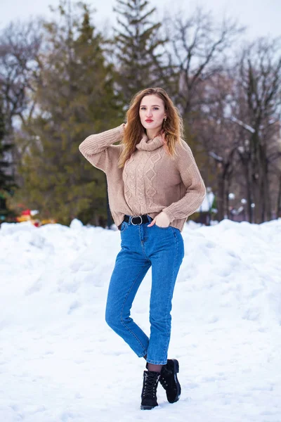 一名身穿米黄色毛衣的年轻漂亮金发女子在冬季公园摆姿势的画像 — 图库照片