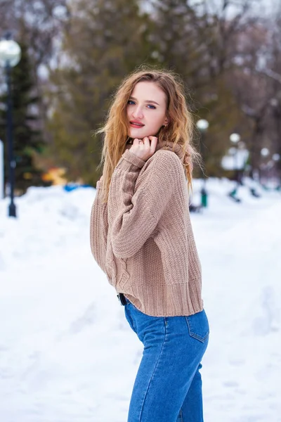 一名身穿米黄色毛衣的年轻漂亮金发女子在冬季公园摆姿势的画像 — 图库照片