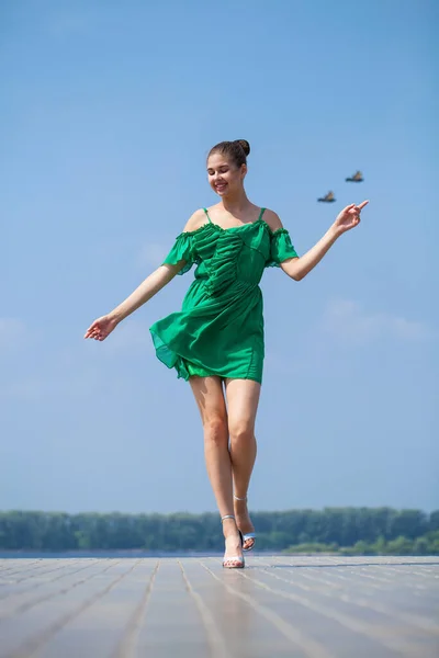 完全な成長の肖像画 通りを歩く緑のドレスを着た若い美しいブルネットの女性 屋外の夏の堤防 — ストック写真