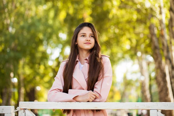 공원의 배경에 분홍색 코트에 아름다운 소녀의 초상화 — 스톡 사진