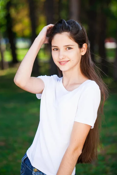 夏季公园背景上一个穿着白色T恤的年轻美丽的黑发女孩的肖像 — 图库照片