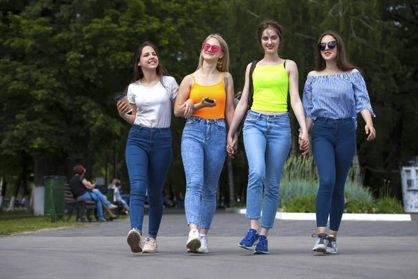 Full body happy women in blue jeans walking in summer park, outdoors