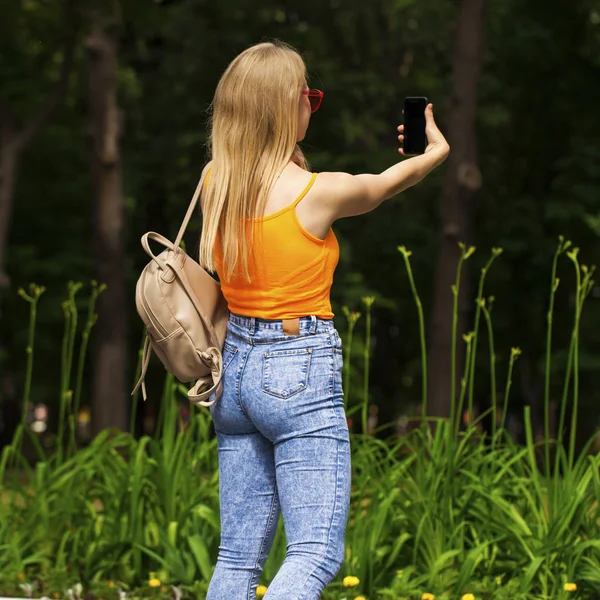 若いです美しいです女の子とともに携帯電話散歩夏公園 — ストック写真