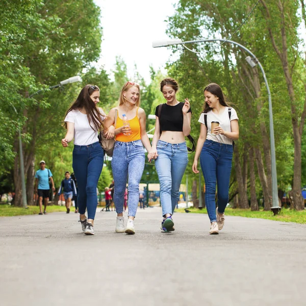 Full body happy women in blue jeans walking in summer park, outdoors